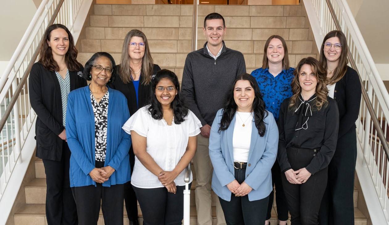 Group photo of CHP Student Services Office standing on a staircase in the Center for Health Sciences building